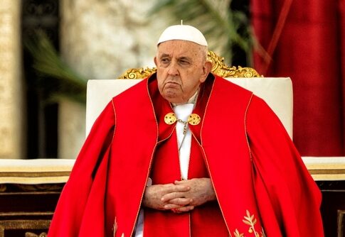 Pope Francis seated in ceremonial red vestments during a formal event