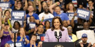 Woman speaking at podium with cheering crowd behind