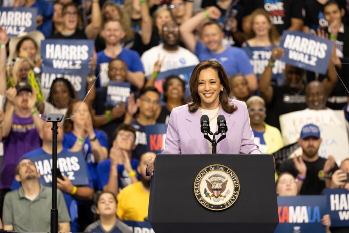 Woman speaking at podium with cheering crowd behind