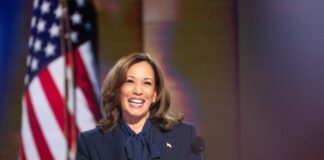 Person smiling at podium with American flag background