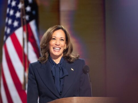 Person smiling at podium with American flag background