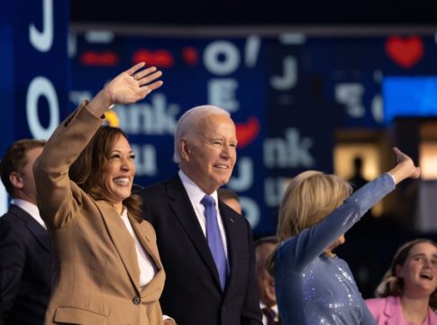 People waving at an event indoors smiling joyfully