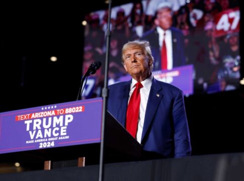 Person standing at podium with audience in background