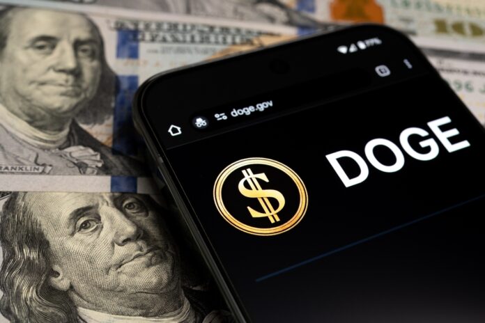 shutterstock_2591039935.jpg featured image Smartphone displaying DOGE app over dollar bills