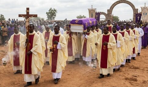 Clergy members in a funeral procession carrying a casket