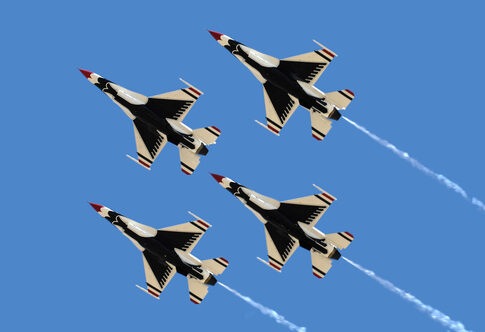 Four military jets flying in formation against a clear blue sky