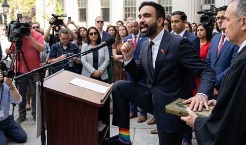 A speaker at a podium passionately addressing a crowd, wearing rainbow socks