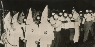 Ku Klux Klan members marching in white robes and hoods.