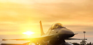 Fighter jet taxiing during sunset on an airstrip.
