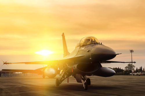 Fighter jet taxiing during sunset on an airstrip.