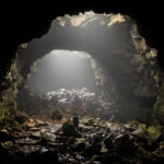 Sunlight entering a dark, rocky cave opening.