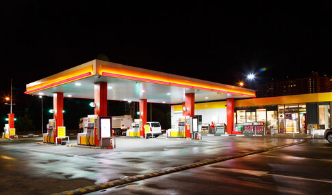 A gas station illuminated at night with fuel pumps and a convenience store